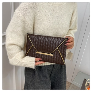 Detail einer dunkelbraunen Umschlag-Clutch mit Webmuster und eleganten Goldmetallelementen