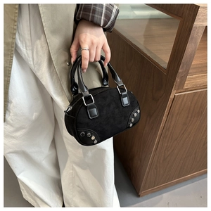 Detail of black matte rivet handbag showing cylindrical handle and metal stud texture