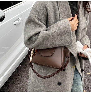 Detail of dark brown vintage shoulder bag with braided strap and retro bead charm