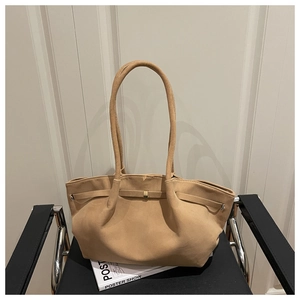 Detail of camel suede tote bag with slim shoulder strap and decorative buckle on a chair