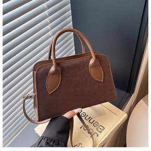 Detail of dark brown suede tote bag with leather handles and minimalist retro design