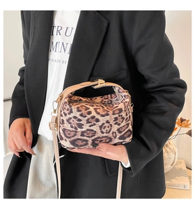 Détail du sac léopard montrant les poignées beiges et les accessoires dorés élégants