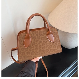 Close-up of leopard print handbag with brown leather handles and gold metal hardware