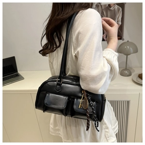 Dettaglio borsa a spalla nera lucida con tasche utility e ciondoli a forma di racchetta