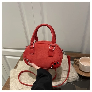 Detail of red faux suede handbag with silver rivets and smooth leather handles