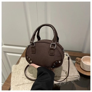 Detail view of dark brown suede egg-shaped bag with metal rivets and shoulder strap