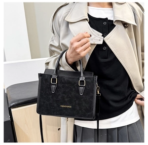 Détail du sac à bandoulière noir mat avec garnitures dorées et inscription stylée