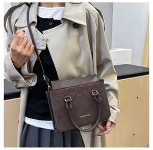 Détail d'un sac à main marron vintage en cuir avec poignées et bandoulière amovible