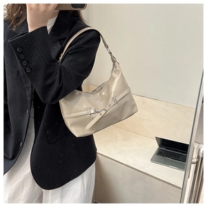 Detail of minimalist cream hobo bag with zipper and metal buckle shown on a model