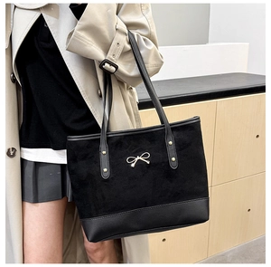 Détail du grand sac cabas noir avec texture suédée et boucle nœud papillon dorée