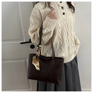 Detail of vintage brown leather tote bag with silk scarf and contrast stitching accents