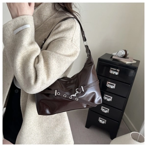 Dark brown faux leather underarm bag with decorative metal eyelet strap shown on a model