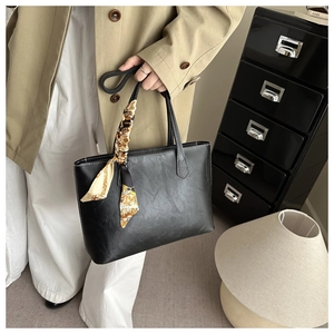Detail of black tote bag with white contrast stitching and elegant patterned silk scarf