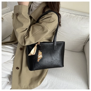 Black faux leather tote bag with printed silk scarf detail on handle, street style view