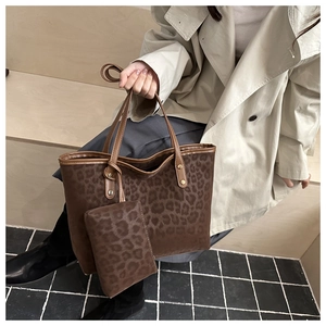 Detail view of large leopard print tote bag and small pouch with metal rivet accents