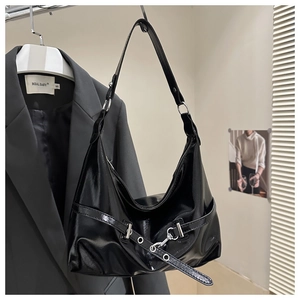 Detail of glossy black patent leather dumpling bag with silver hardware and eyelets