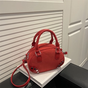 Elegant red suede Boston bag with silver rivets and shoulder strap on white books