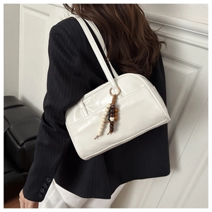 Detail of white leather pillow bag with wooden bead charm and elegant shoulder strap