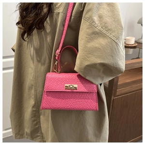Detail of fuchsia woven crossbody bag with gold metallic clasp and matching shoulder strap