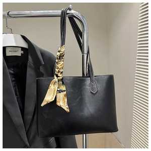 Detail of black tote bag with white stitching and decorative silk scarf handle wrap