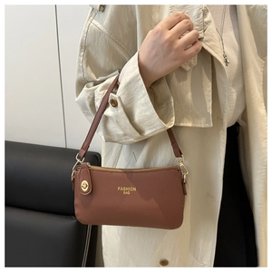 Close-up of brown litchi pattern leather baguette bag with golden metal hardware detail