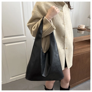 Minimalist black oversized tote bag worn by a model in a stylish indoor setting