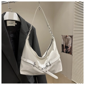 Detail of off-white glossy faux leather handbag hanging on a black blazer jacket