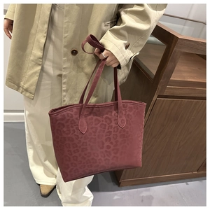 Close-up of a burgundy leopard print tote bag with soft suede texture and top handles