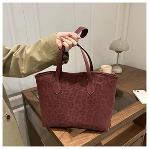 Close-up of a burgundy leopard print tote bag with a matte texture and slim handle
