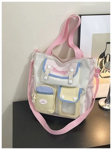 Close-up of color-block tote bag with multiple pockets and pink handles in a cozy setting