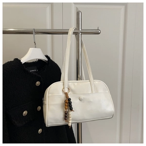 Detail of white glossy shoulder bag with wooden bead charm and front pocket on hanger