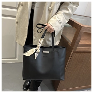 Détail du sac cabas noir avec foulard en soie et plaque métallique argentée élégante