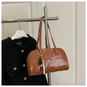 Close-up of brown patent leather hobo bag with colorful wooden bead charm detail