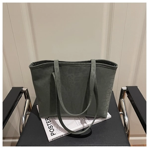 Detail of dark green leopard print suede tote bag resting on a magazine and chair