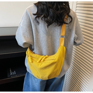 Close-up of a bright yellow nylon crescent crossbody bag with braided zipper pulls