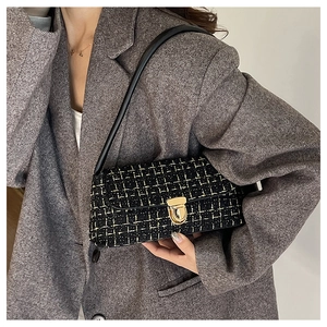 Détail du sac sous le bras en tweed avec fermoir doré et bandoulière en cuir noir