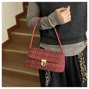 Détail du sac sous le bras en tweed rouge avec fermoir doré et bandoulière en cuir