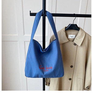 Close-up of blue tote bag with 'C'est la vie' embroidery and durable canvas texture