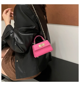 Detail of bright pink crocodile pattern mini bag with metal lock and chain strap