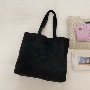Flat lay of black corduroy tote bag with knitted accessories and magazine for winter