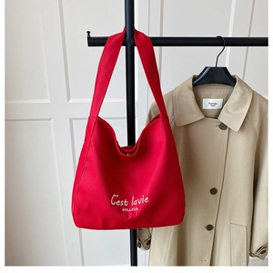 Close-up of red canvas tote bag with white lettering and silver magnetic metal snap button