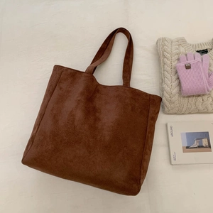 Close-up of brown suede tote bag with minimalist dual handles on a neutral background
