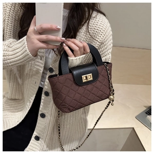Close-up of quilted handbag with gold twist lock and chain strap on knitwear background