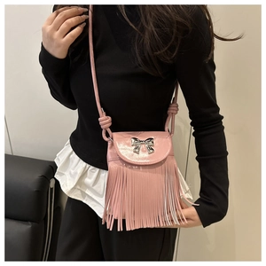 Detailed view of pink crossbody bag with silver bow and flowing fringe detail