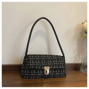 Dettaglio della borsa a tracolla in tweed nero con fibbia dorata e trama a quadri