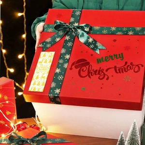 Christmas gift box with red lid and green ribbon featuring merry Christmas gold foil print