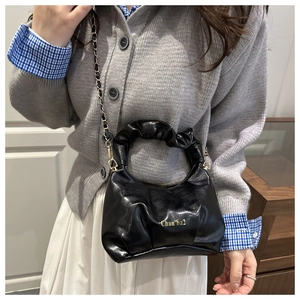 Détail du sac nuage noir plissé avec chaîne métallique et lettrage sur le cuir brillant