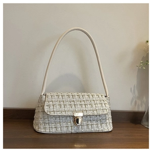 Dettaglio della trama in tweed crema e della fibbia dorata su questa borsa a spalla