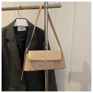 Detail of minimalist underarm bag featuring suede patchwork and a gold circular lock buckle