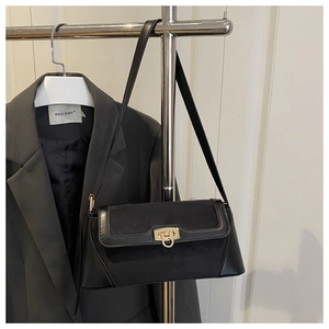 Detail of black leather shoulder bag with gold clasp and textured suede stitching